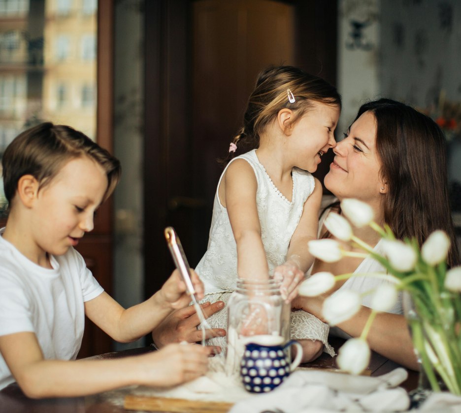 A mother and her two children laughing at the kitchen table