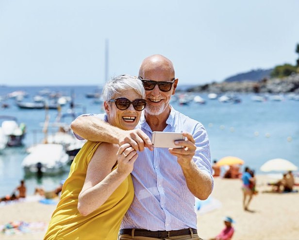 A retired couple taking a photo together on the beach